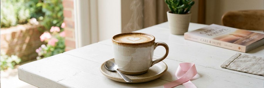 Taza de café con lazo rosa representando la investigación sobre café y prevención del cáncer de mama — NutriPsicoGen